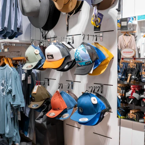 Gorras de estilo surf con diseños variados expuestas en tienda de moda surf en Lanzarote.