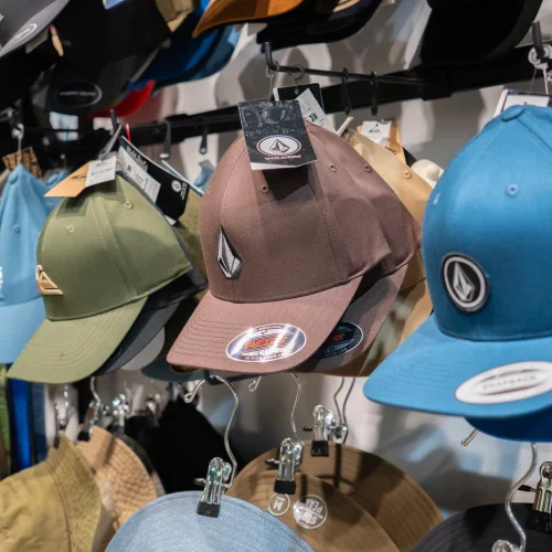 Gorras de estilo surf con diseños variados expuestas en tienda de moda surf en Lanzarote.