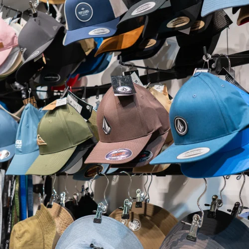 Gorras de estilo surf con diseños variados expuestas en tienda de moda surf en Lanzarote.