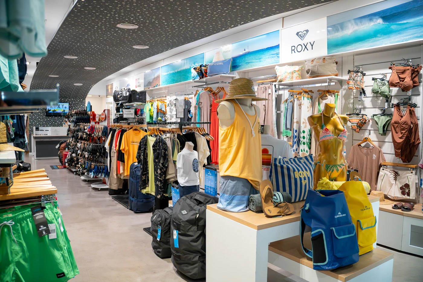 Tienda de ropa de surf con nueva colección en Lanzarote, mostrando camisetas, mochilas y accesorios de moda surf.