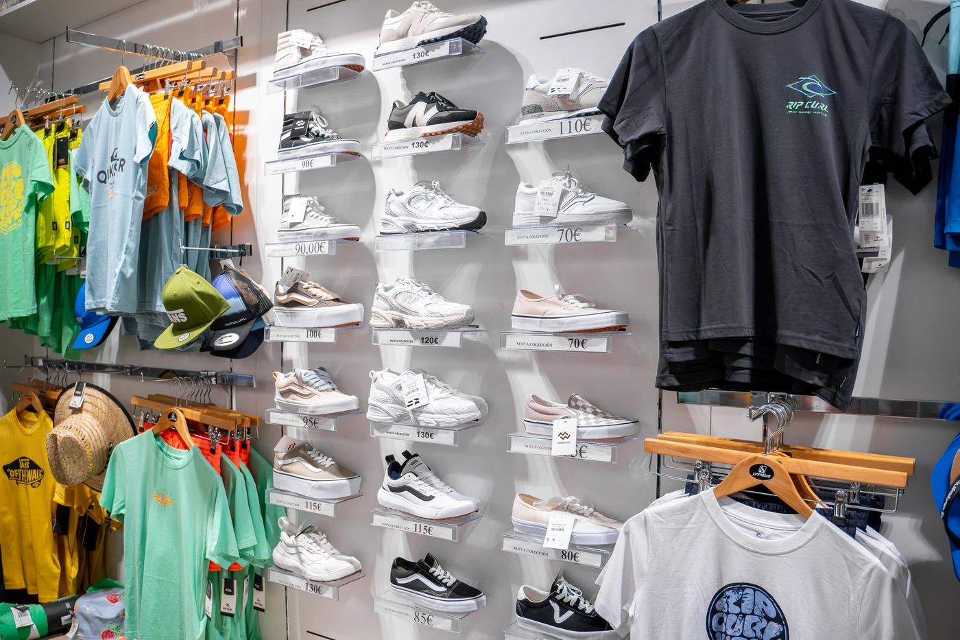 Pared de exhibición con zapatillas deportivas y camisetas estilo surf en una tienda de moda surf en Lanzarote.