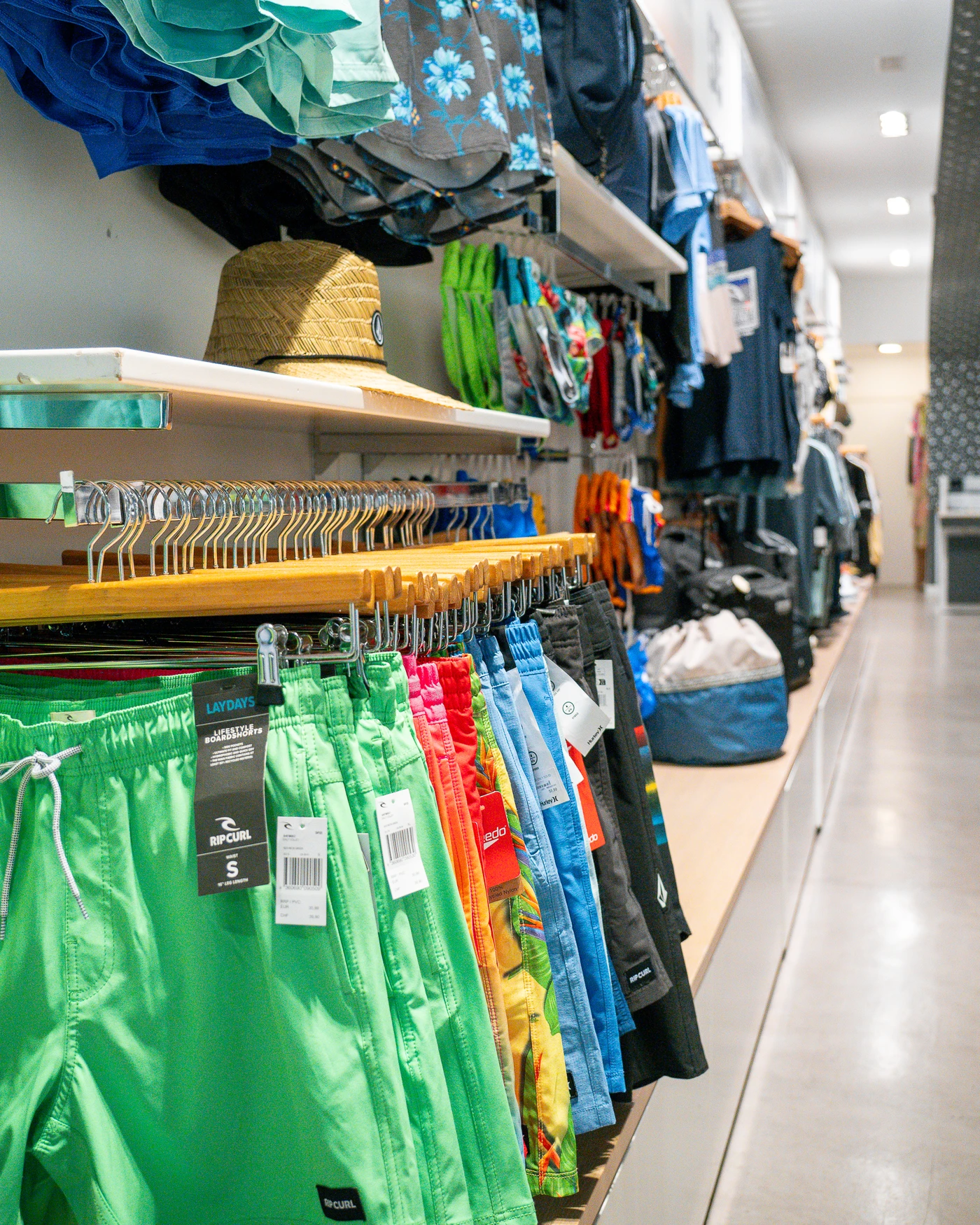 Tienda de ropa de surf con nueva colección en Lanzarote, mostrando camisetas, mochilas y accesorios de moda surf.