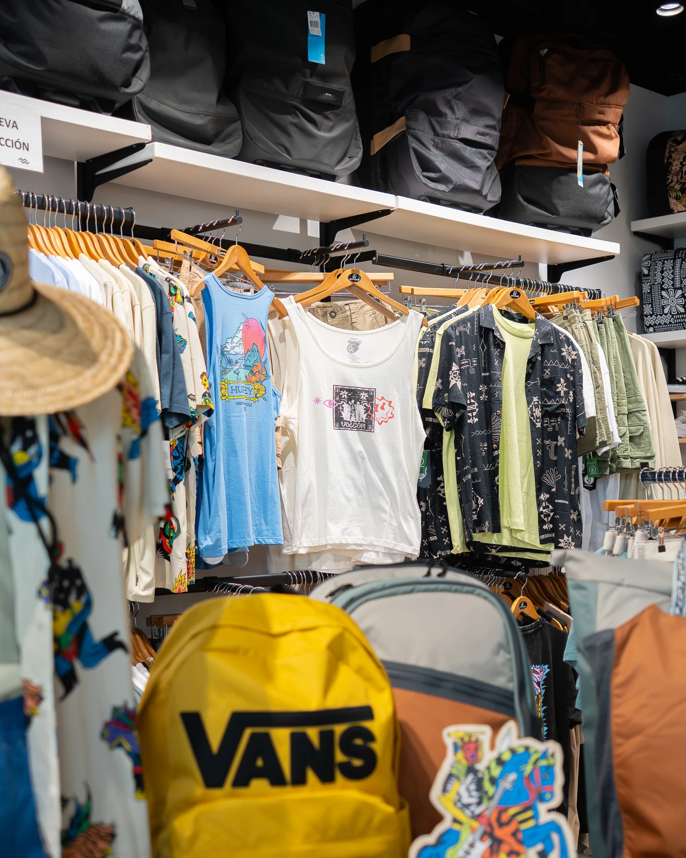 Tienda de ropa de surf con nueva colección en Lanzarote, mostrando camisetas, mochilas y accesorios de moda surf.