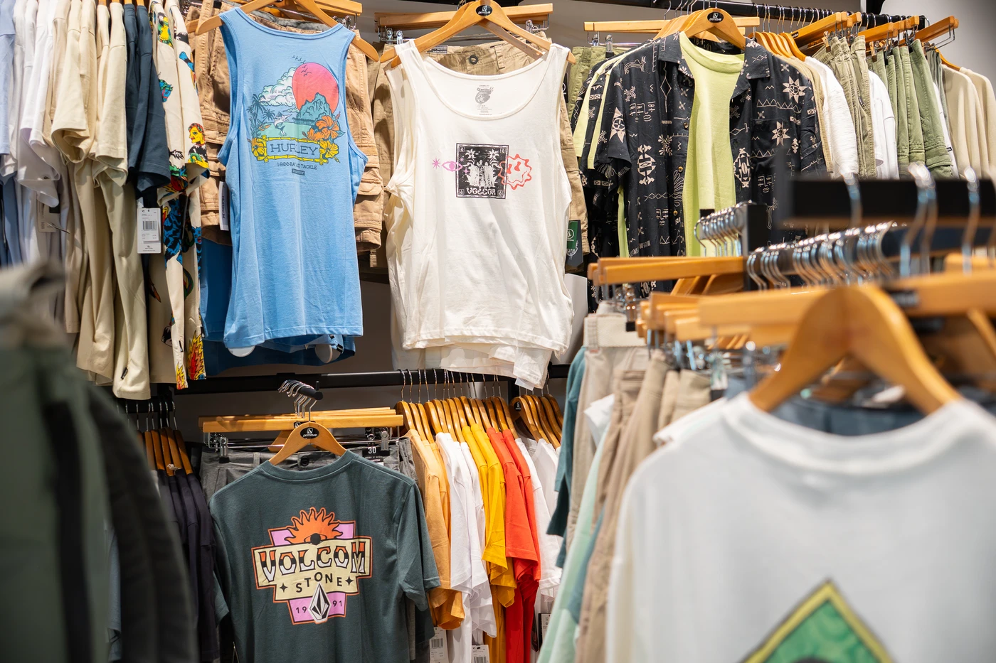 Tienda de ropa de surf con nueva colección en Lanzarote, mostrando camisetas, mochilas y accesorios de moda surf.